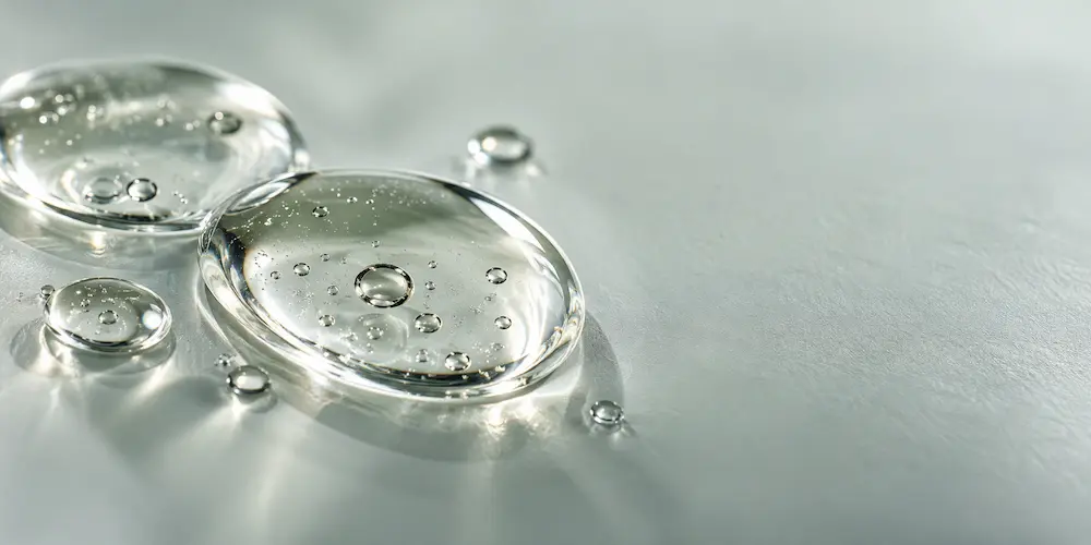 Makroaufnahme transparenter Serumtropfen auf heller Fläche